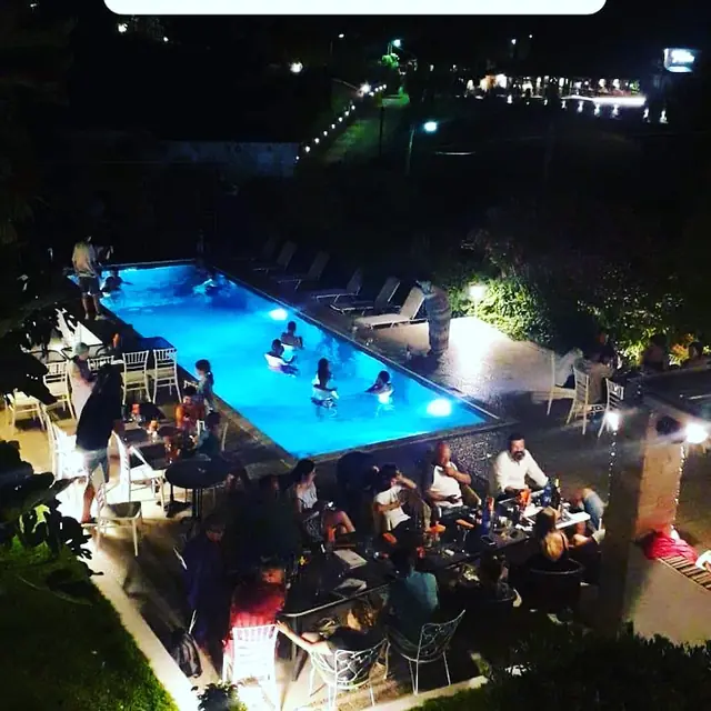 The pool and the terrace full of guests, seen from above at night